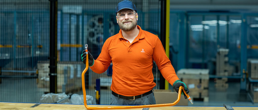 A man wearing a hat and gloves holding a an aluminium busbar