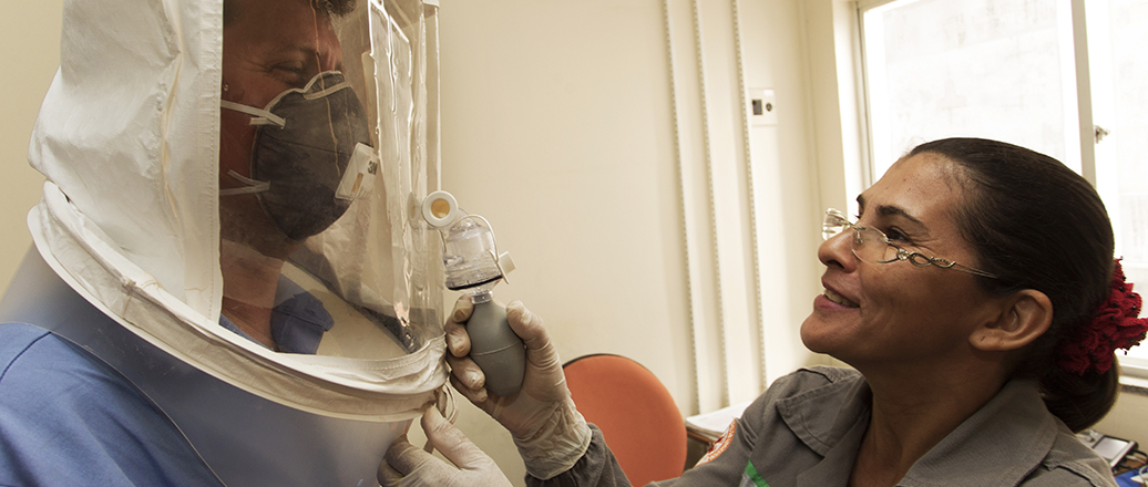 woman dressing man in hazmat suit