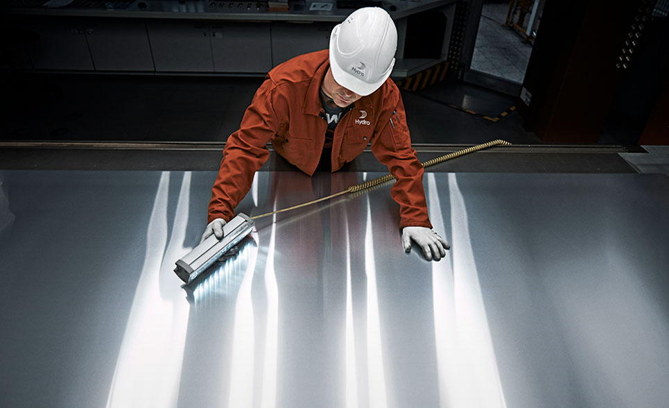 worker inspecting aluminum plate