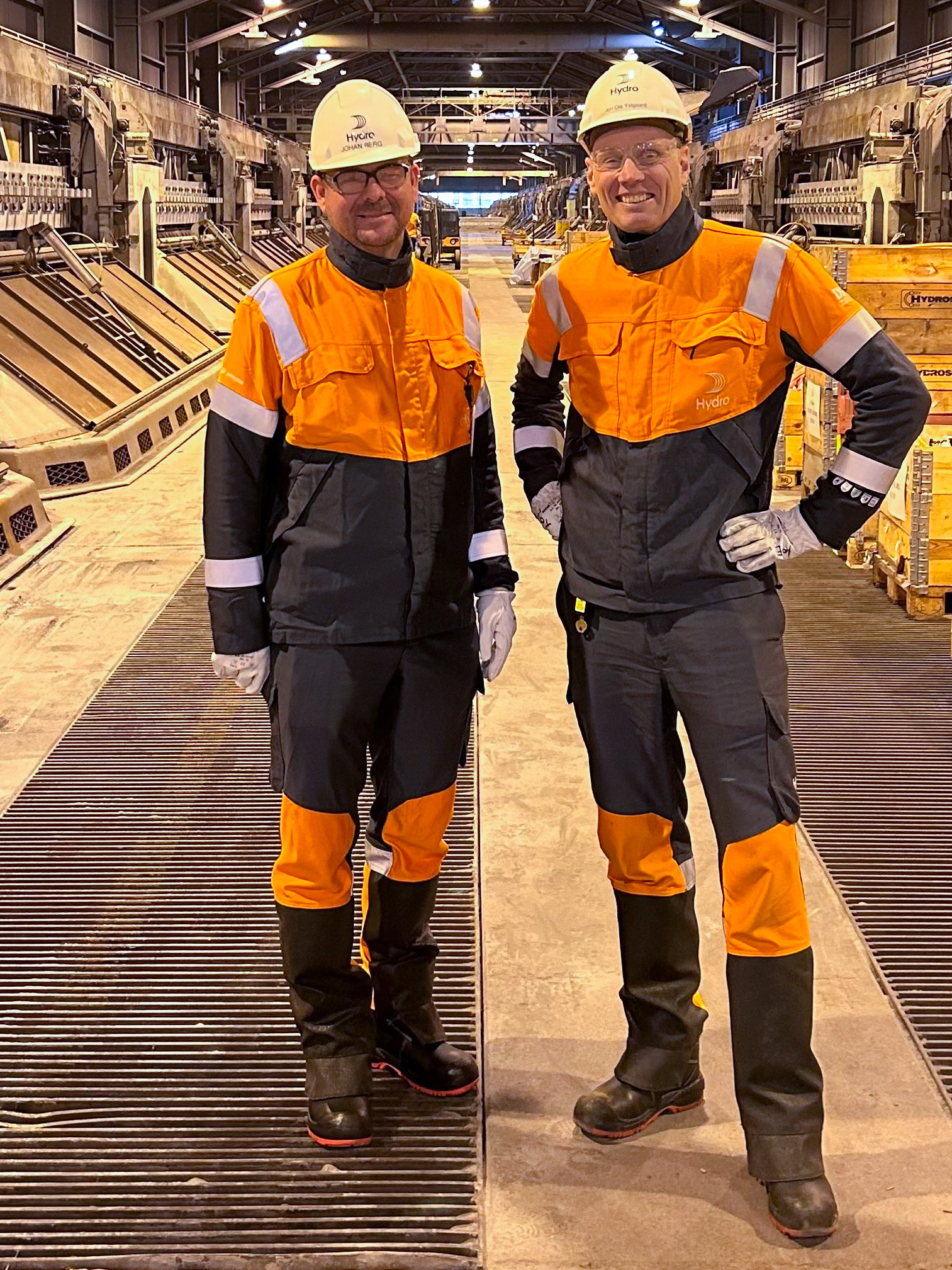 a couple of men in safety gear standing on a factory floor
