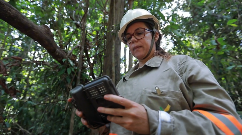 a woman in a hard hat and a white helmet holding a device