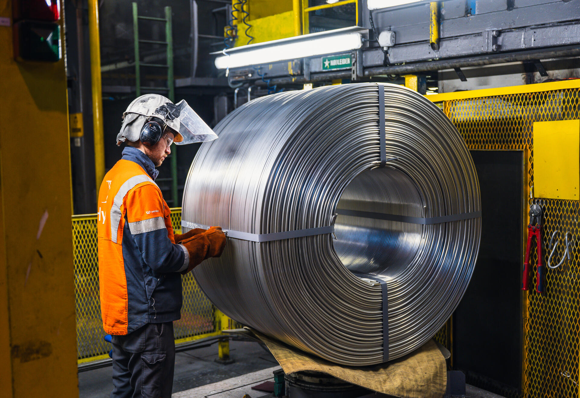 a man in a factory with a large roll of metal
