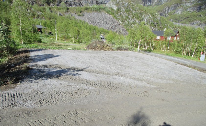 a dirt road with a house on the side