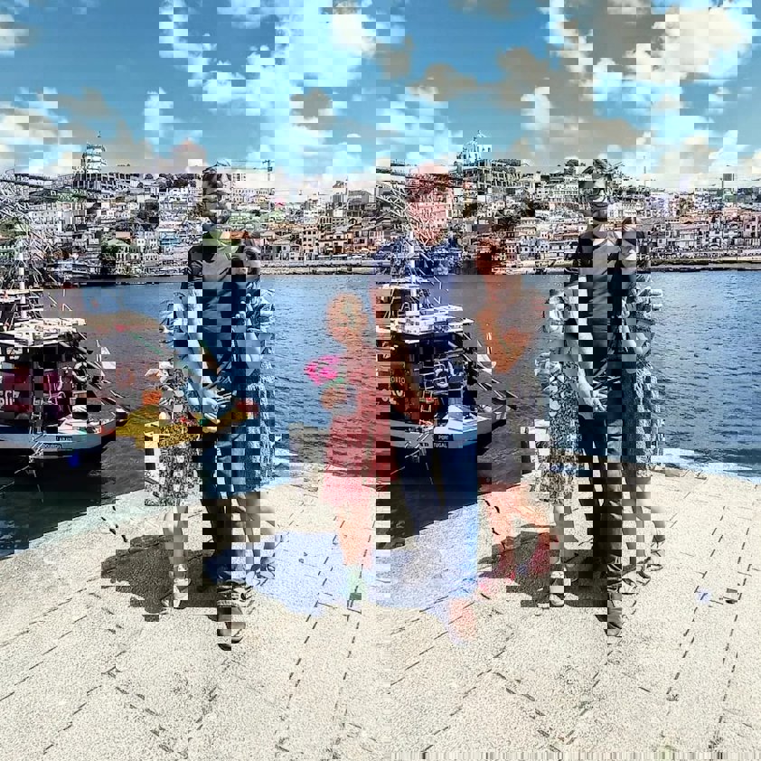 a group of people posing for a photo on a dock by a body of water